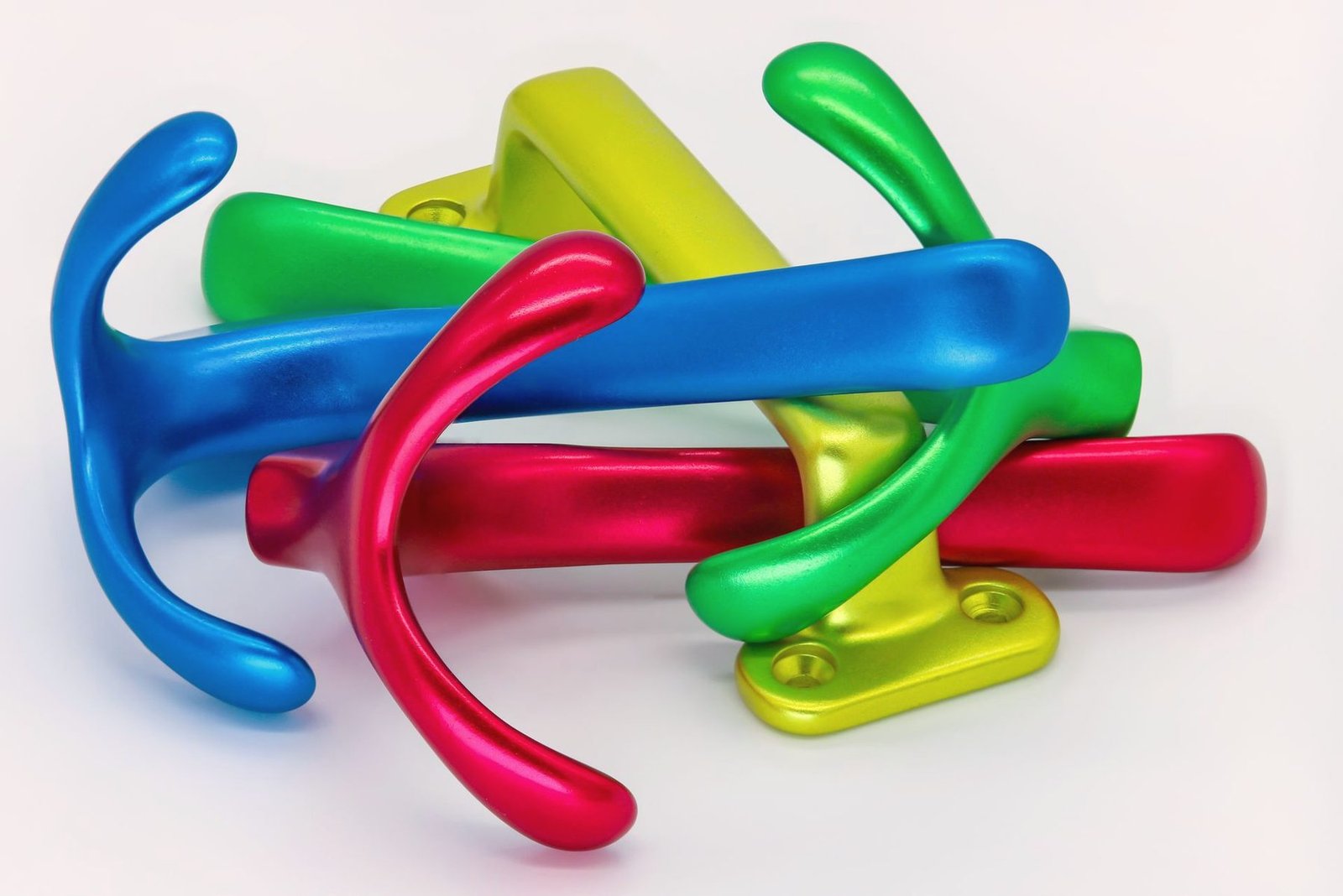 Small coated steel hooks in red, green, blue and yellow laid on a white surface.