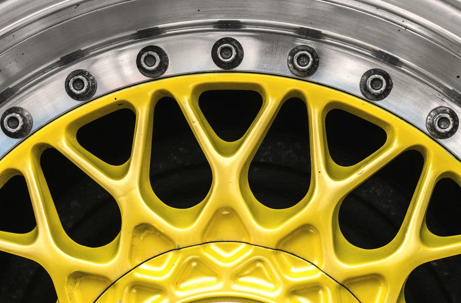 Close view of a wheel coated in a deep yellow finish, lug holes in the foreground.